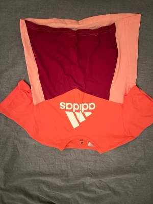 Adidas tränings t-shirt i bomull - Cool t-shirt från Adidas i korall, vinröd och ljusrosa. Perfekt till ungdomar i åldern 13-14/164. Prislappen är kvar (originalpris 229 kr)
