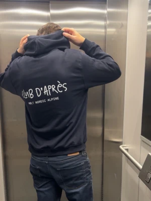 CLUB D’APRÈS Hoodie - Club d’Après - den perfekta hoodien för afterski, stadsliv och allt däremellan. Simpel, mjuk och stilren.