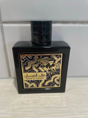 Qaed Al Fursan parfym - Qaed Al Fursan från Lattafa har en unik design med guld- och svartmönster samt en springande häst på etiketten. Perfekt för dig som vill sticka ut med en parfym som utstrålar energi och stil.