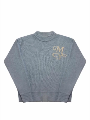 Blå stickad tröja med M-broderi - Snygg blå stickad tröja med ribbad hals och muddar. På bröstet finns ett broderat M i beige som ger en unik touch. Perfekt för dig som gillar stilrena detaljer och vill ha något som sticker ut lite extra.