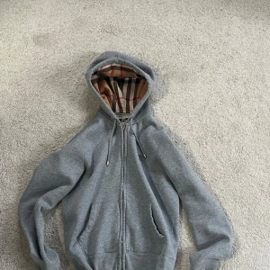 Burberry zip hoodie storlek Xs - Säljer min burberry hoodie då den är för liten för mig. Tyvärr har ena dragkedjan ramlat av (se bild 5) men det är något man kan fixa själv. Har tyvärr inget kvitto då jag fick tröjan men den är köpt på nk i Stockholm. 