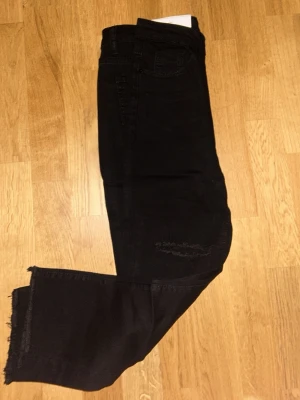Svarta jeans med rå kant - Svarta jeans med snygg rå kant längst ner på benen och klassisk femficksdesign. Jeansen har en rak passform och är tillverkade i ett mjukt jeansmaterial. Perfekta för dig som gillar en enkel men cool stil.