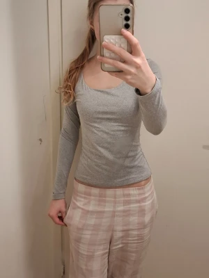 Grå tröja - Säljer en enkel och stilren grå långärmad topp i storlek XS. Toppen har rundad halsringning och är figurnära med en slim passform. Materialet känns mjukt, perfekt att matcha med jeans eller kjol.