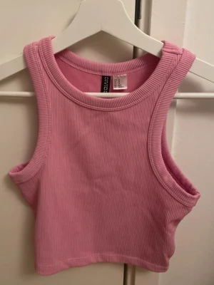 Rosa ribbad topp - Säljer en croppad rosa linnetopp från H&Ms egna märke Divide i storlek XS. Toppen är ribbad. Använd få gånger, skriv för fler bilder!