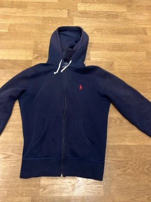 Ralph lauren zip-hoodie (FRI FRAKT) - En snygg mörkblå zip-hoodie från Ralph lauren. Passar perfekt om man är ungefär 160-170 cm lång. Hör av dig om du har några funderingar! Pris kan diskuteras.