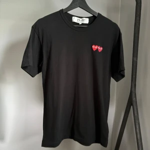 Comme des Garçons Play t-shirt - Snygg och stilren t-shirt från CDGP i riktigt bra skick utan några defekter. Köpt på NK för 1049 kr. Den är i strl L men väldigt liten i storleken. Hör av er vid funderingar!