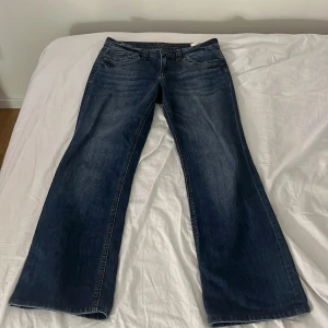Blå bootcut jeans med breda ben - Snygga blå jeans med bootcut-modell och breda ben. Klassisk femficksdesign och coola slitningar framtill. Jeansen har normal midja och är tillverkade i robust denim som ger en avslappnad vibe.