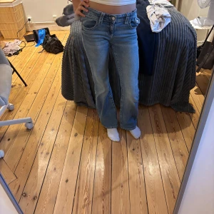 Blå bootcut jeans från Gina Tricot - Snygga blå jeans från Gina Tricot i storlek 158. Modellen har bootcut-ben och coola broderade detaljer på bakfickorna. Klassisk femficksdesign och normal passform. Perfekta för dig som gillar en avslappnad men trendig look.