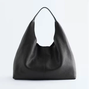 Svart axelväska i skinn - Stilren svart axelväska i mjukt skinn med minimalistisk design. Väskan har en rymlig insida och bred axelrem som gör den bekväm att bära. Använd ett fåtal gånger. Så den är i bra skick. Ordinarie pris 1290kr.