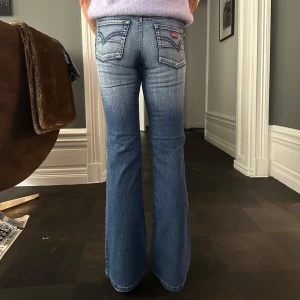 Bootcut, lowwaist jeans  - Säljer dessa supersnygga och unika lågmidjade och utsvängda jeansen från dragonking! Storlek 34. Midjemått: 34,5cm. Innerbenslängd: 80cm. Ytterbenslängd: 104 cm Endast använd en gång så väldigt bra skick!! Modellen på bilden: 172cm, med långa ben.