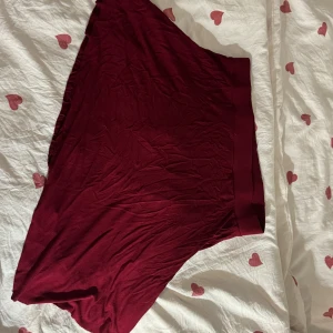 Vinröd kjol från Nelly i bomull - Säljer en vinröd kortkjol från Nelly i mjuk bomull. Kjolen har en bred resår i midjan och är enkel i modellen utan mönster eller detaljer. Perfekt för dig som gillar en basic och bekväm stil. Den är asymmetrisk. Kan skicka bild om det behövs hur den ser ut på