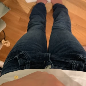 Mörkblå bootcut jeans - Säljer ett par mörkblå jeans med bootcut-modell. Jeansen har klassisk femficksdesign och är tillverkade i ett mjukt denimtyg som sitter skönt. Perfekta om du gillar en lite utsvängd look nertill och vill ha en tidlös stil. Lite korta 