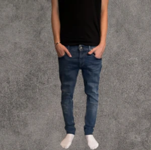 Slim blå jeans från T/J, 30/32 - Slimmade blå jeans från T/J med klassisk femficksdesign och snygga slitningar. Jeansen har normal midja och raka ben med rå kant nertill för en cool look. Tillverkade i bomull och passar perfekt till en avslappnad stil. Några trådar har gått av från änden men det är ej någon skada och det är ej något som syns eller märks🙌