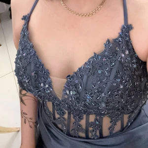 Blå långklänning med spets och slits - Snygg långklänning i mörkblå satin med blommig spets och pärldetaljer upptill. Klänningen har smala axelband, öppen rygg med snörning och en hög slits framtill. Perfekt för bal eller fest, ger en elegant och glam känsla.priset kan diskuteras!