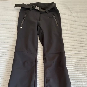 Svarta skidbyxor - figurnära med flare - Jättefina svarta skidbyxor från 8848 Altitude med bälte i midjan och dragkedjor både vid fickor och benslut. Fin passform, figurnära och flare. Endast använda ett par gånger.