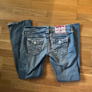 True Religion Jeans – Strl 26 (Low Rise & Flare) - True Religion Jeans – Strl 26 (Low Rise & Flare) Riktigt snygga True Religion jeans i klassisk blå denim med slitningar och kontrastsömmar. Modellen är low rise med utsvängda ben (flare), vilket ger en tidlös men ändå trendig look.         📏 Midja: 37 cm                                                        📏 Innerbenslängd: 74 cm  📏 Storlek: 26  vill helst bli av med så snabbt som möjligt därför är priset lite längre än vanligt