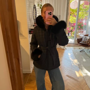 Vintage Svart quiltad jacka med pälsdetaljer - Quiltad svart jacka med fluffiga pälsdetaljer på krage och ärmslut. Storlek 42 och i toppenskick. Äkta päls. 