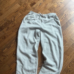 Grå mjukisbyxor från Pull&Bear L - Grå mjukisbyxor från Pull&Bear i storlek L. Byxorna har resår och snörning i midjan, två sidofickor och en liten logga på ena benet. Tillverkade i mjukt bomullsmaterial som är riktigt skönt mot huden.