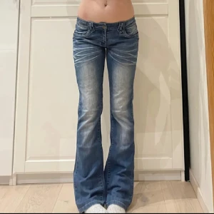 Lågmidjade bootcut jeans  - Snygga blå bootcut jeans från med låg midja och slitningar framtill. Jeansen har klassiska fem fickor, dekorativa sömmar och en cool logga på bakfickan. Perfekt passform och stretchigt denimtyg för en bekväm känsla.