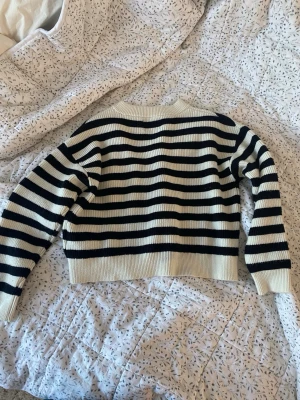 Randig stickad tröja från Zara - Säljer en snygg stickad tröja från Zara i storlek 140. Tröjan är vit med svarta horisontella ränder, har rund hals och långa ärmar. 