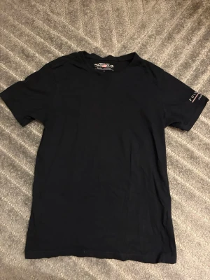 Svart t-shirt Polo Club Saint Vincent - Svart t-shirt från Polo Club Saint Vincent med tryck på ena ärmen. Klassisk rund hals och korta ärmar. perfekt för dig som gillar stilrena plagg.