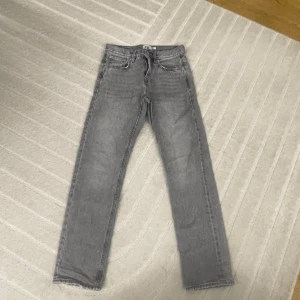 Grå raka jeans från 157 - Säljer ett par grå jeans från 157 med klassisk femficksdesign och raka ben. Jeansen har normal passform och dragkedja i gylfen. Perfekta till en avslappnad stil och funkar året runt.