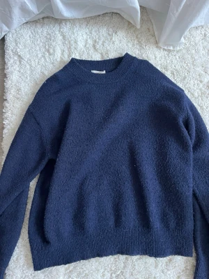 Mörkblå stickad tröja Gina Tricot - Mysig mörkblå stickad tröja från Gina Tricot i storlek 146/152. Tröjan har rund halsringning, ribbade muddar och en loose passform. Perfekt för kyliga dagar och enkel att matcha med jeans/kostymbyxor eller mjukisbyxor.