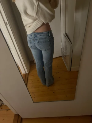 Ljusblå low waist bootcut jeans - Säljer ett par ljusblå jeans med låg mid face och bootcut passform. Klassisk femficksmodellright och synliga knappar som ger en snygg detalj. Jeansen är i mjukt denimtyg och har en avslappnad vibe, perfekta till en stick ev tröja eller crop top. Storlek 152