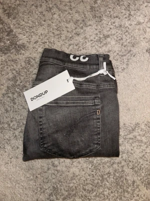 Gråa  Dondup George jeans - Snygga grå jeans från Dondup med klassisk femficksdesign och diskret D-detalj på bakfickan. Jeansen har en rak passform och är tillverkade i mjukt bomullsmaterial med lite stretch för extra komfort. Perfekta för dig som gillar stilrena jeans, nypris ~3400kr. Vårt pris är EJ prutbart. Hör av er vid intresse/ frågor!