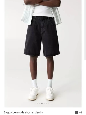Baggy svarta bermudashorts i denim - Baggy bermudashorts från Pull and Bear i svart denim. De har en loose passform, klassisk femficksdesign och knappgylf. Sköna o använda några få gånger 