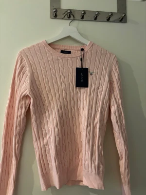 Ljusrosa Gant tröja - Säljer en ljusrosa tröja från GANT i storlek M. Rund i halsen och lång ärm. Har en diskret GANT logga på bröstet.
