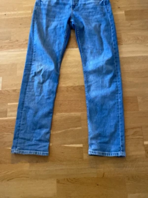 Blå raka jeans från Kappahl, stl 158 - Snygga blå jeans från Kappahl i rak modell. Klassisk femficksdesign och normal passform. Jeansen är tillverkade i jeansmaterial och har en ljusblå tvätt som ger en fräsch look. Perfekta för dig som gillar enkel och tidlös stil.
