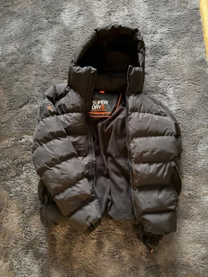 Vinterjacka Superdry pufferjacka - Superdry pufferjacka – Storlek S – Nyskick Snygg och varm Superdry pufferjacka köpt på Stadium. Jackan är bokstavligen oanvänd, endast provad – säljs då sonen inte fastnade för modellen. ✔ Storlek S ✔ Nyskick ✔ Kvitto finns  Perfekt jacka för vinter. Bara att höra av sig vid intresse! Pris: 750kr