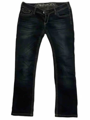 Mörkblå jeans från Soccx med kontrastsömmar - Säljer ett par mörkblå jeans från Soccx med tydliga kontrastsömmar och snygga detaljer på bakfickorna. Jeansen har låg midja och klassisk femficksdesign. Materialet är jeans med stretch för skön passform. Perfekta till en avslappnad look.