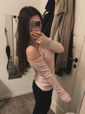 Ljusrosa offshoulder topp - Säljer en ljusrosa offshoulder topp med långa ärmar. Toppen har en avslappnad passform och är tillverkad i ett mjukt material som känns skönt mot huden. Perfekt för dig som gillar en stilren och feminin look.