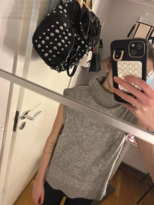 Grå stickad poloväst - Mysig grå stickad väst med hög polokrage och ärmlös design. Perfekt att slänga över en skjorta eller långärmad tröja för en chill och trendig look. Västen har en rak passform och mjukt material som känns skönt mot huden.