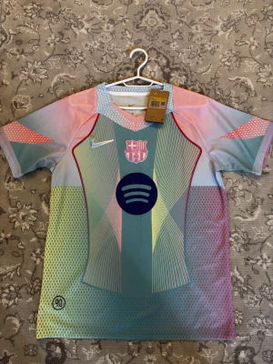 FC Barcelona Nike tröja - Säljer en FC Barcelona x Nike matchtröja i storlek S. Tröjan har ett unikt pastellmönster i blått, rosa, gult och grönt med klubbmärke och Nike-logga på bröstet. Materialet är lätt och andas, perfekt för fotboll eller streetwear.