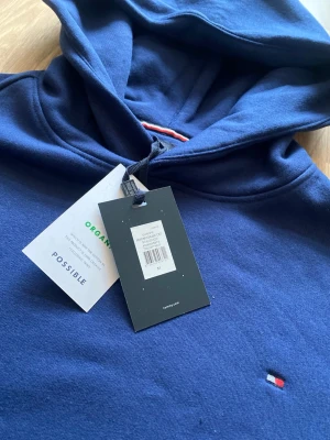 Navy Blue Tommy Hilfiger Hoodie - Det här är en helt sprillans ny marinblå Tommy Hilfiger hoodie, aldrig andvänd innan för ett bra pris. SKU007.TH.HOOD.M