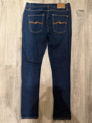 Nudie Jeans Lean Dean Dry 16 Dips - Sjukt snygga Nudie Lean Dean Dry 16 Dips jeans i mycket fint skick i storlek W32/L32. Dessa jeans får snygg fade över tid om man använder dom mycket. Mått - Midja: 40cm, Benlängd: 100cm. Modellen är 185cm & 63kg. Hör av dig vid funderingar!🤝
