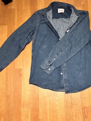 Blå jeansskjorta från Vailent - Säljer en klassisk blå jeansskjorta från Vailent i storlek S. Skjortan har långa ärmar, knappar framtill och en snygg krage. Tillverkad i bomull och passar perfekt för en avslappnad stil. Enkel och tidlös design som är lätt att matcha.   Den är aldrig använd ändad prövad. Pris lapp fins kvar.    Ny pris 750kr.     Pris it hugget i sten.