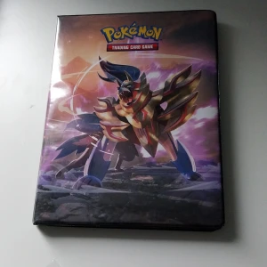 Pokémon Trading Card Game Samlarpärm 100+ kort - Cool samlarpärm för Pokémon Trading Card Game med snygga illustrationer av Zamazenta och Zacian. Perfekt för dig som vill organisera och visa upp dina Pokémonkort! Inuti finns flera kort, bland annat klassiker som Bulbasaur, Caterpie och Kyogre. Ett måste för alla Pokémonfans och samlare!