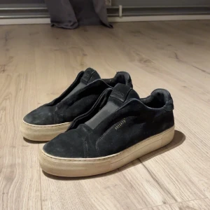 Svarta sneakers från Axel Arigato - Snygga svarta sneakers från Axel Arigato med stilren design och beige platt sula. 6,5/10 