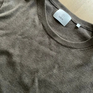 Brun stickad tröja från Black - Snygg brun stickad tröja från Black i storlek M. Tröjan har rund halsringning och långa ärmar, perfekt för dig som gillar en enkel och stilren look. Materialet är mjukt och skönt mot huden, och den neutrala färgen gör den lätt att matcha med allt.