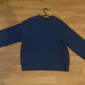 Mörkblå stickad tröja från 157 XS - Mysig mörkblå stickad tröja från 157 i storlek XS. Tröjan har en klassisk rund hals och långa ärmar, perfekt för att hålla värmen under kyliga dagar. Materialet är grovstickat och ger en skön och avslappnad vibe. Enkel att matcha med jeans eller kjol.