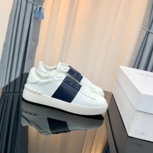 Valentino Open sneakers vit marinblå - Snygga Valentino Open sneakers i vitt skinn med bred marinblå rem över sidan och coola nitar vid hälen. Platt sula och rund tå ger en clean look, perfekt för dig som gillar exklusiva märken och stilren design. PRIS KAN DISKUTERAS