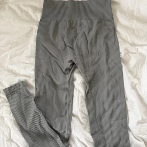 Grå ribbade leggings från 157 - Säljer ett par grå leggings från 157 i storlek medium. De har ribbad struktur och hög midja som sitter skönt och ger en snygg siluett. 