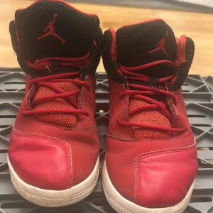 Röda Nike Air Jordan sneakers - Säljer ett par röda Nike Air Jordan sneakers med svarta detaljer och vit sula. Skorna har klassisk Jumpman-logga på plös och häl, snörning och meshpartier för extra andningsförmåga. Perfekta för dig som gillar streetstyle och vill sticka ut.