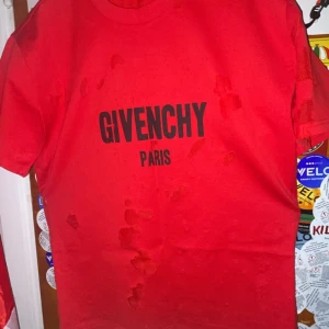 Röd Givenchy Paris t-shirt - Snygg röd t-shirt från Givenchy Paris med svart logga tryckt framtill. Klassisk rund halsringning och korta ärmar. T-shirten är i mjuk bomull och har en clean, stilren look som passar perfekt till jeans eller shorts.