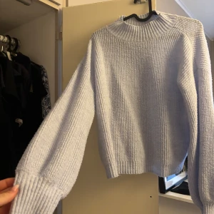 Ljuslila stickad tröja med breda ärmar - Supermysig ljuslila stickad tröja med breda, ribbade ärmslut och hög ribbad hals. Tröjan har en loose fit och är perfekt för kyliga dagar. Enkel men stilren design som passar till allt.