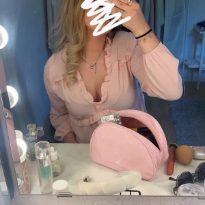 Ljusrosa blus - Säljer en ljusrosa blus med v-ringning och volangdetaljer längs halsringningen och under bysten. Bara använd fåtal gånger.